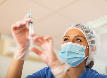 Young woman doctor assistant preparing syringe for injectionの写真素材