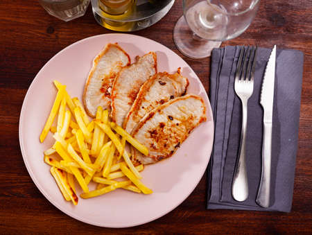 Tasty hearty lunch of roasted steaks of pork loin served with fried potatoesの写真素材