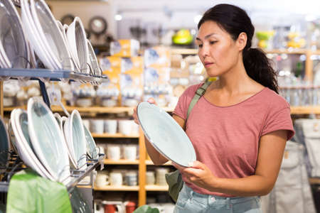Asian woman choosing dishes at decor storeの写真素材