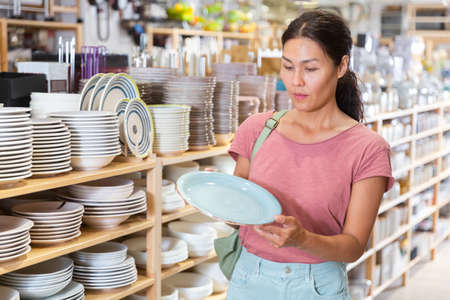 Asian woman choosing dishes at decor storeの写真素材