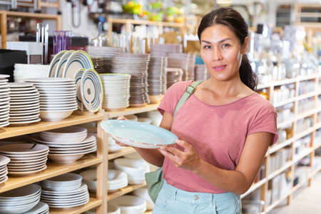 Asian woman choosing dishes at decor storeの写真素材