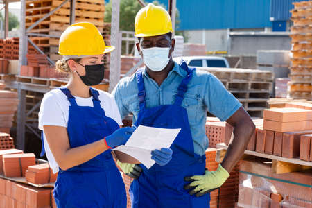 Two workers in masks keep track of the number of redbricksの写真素材