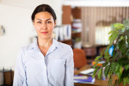 Positive confident Asian businesswoman standing in modern office