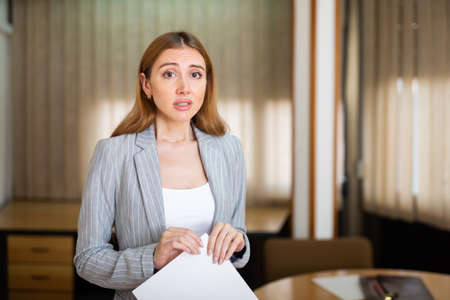 Frustrated young female entrepreneur with papers in officeの写真素材