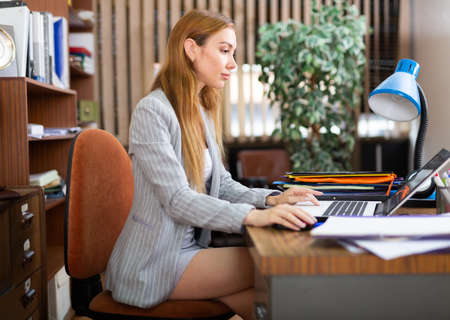 Female secretary working on laptop in officeの写真素材