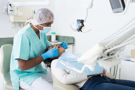 Dentist with woman patient during oral checkup in dental officeの写真素材