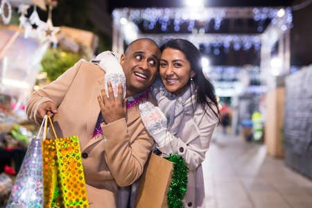 Happy married couple with packages of gifts at new year fairの写真素材