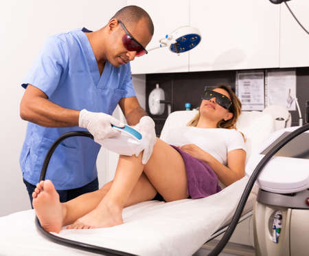 Latina receiving hardware hair removal on legs in aesthetic clinicの写真素材