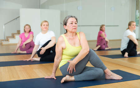 Women exercising during yoga class in fitness center - marichiasana poseの写真素材
