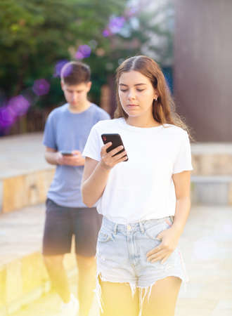 Two teenagers with smartphones are walkingの写真素材