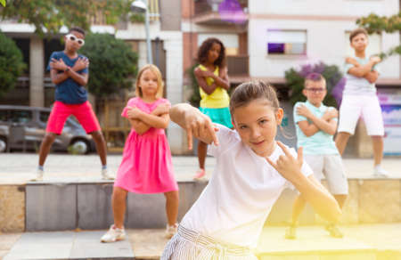 Preteen b-girl dancing with group of friends on city streetの写真素材