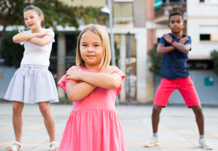 Positive girl dancing modern choreography with group of tweenagers outdoorsの写真素材