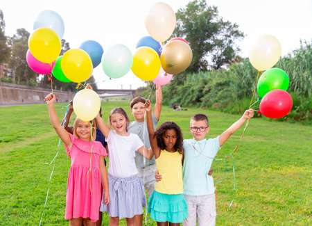 Barefoot kids playing with balloons on grassの写真素材