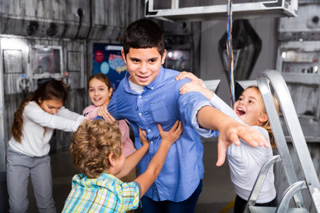 Children restraining boy trying to reach out something in escape room