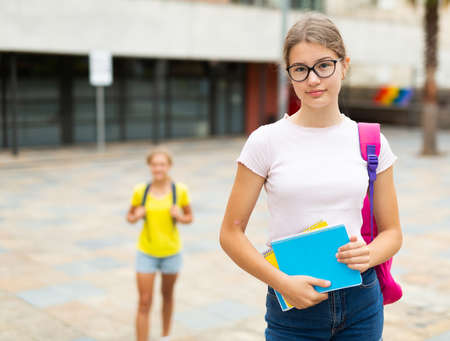 Girl with copybooks standing beside school buildingの写真素材