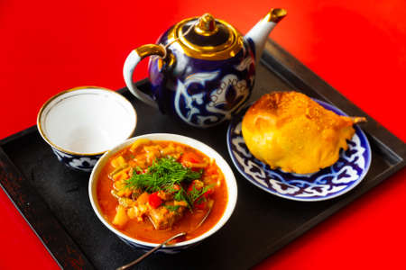 Uzbek laghman, samsa, teapot and cup on trayの写真素材