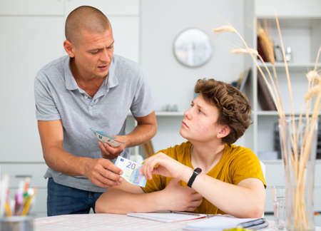 Teenager son asking father to give him moneyの写真素材