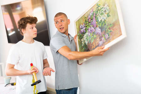 Father and his son hanging picture on wallの写真素材