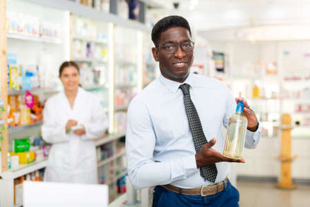 African american male chooses a therapeutic shampoo, to buyの写真素材