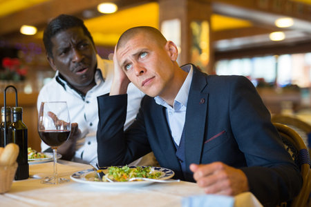 Man talking with upset friend at restaurant
