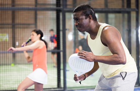 Sporty afro american man playing padel tennis indoor