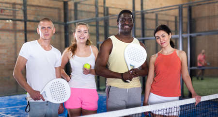 Cheerful team of men and women after playing padel on tennis courtの写真素材