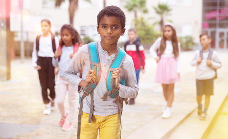 African american boy standing near school, children on backgroundの写真素材