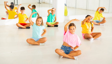 Group of children exercising during yoga class in fitness center - vakrasana pose