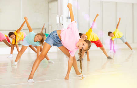 Kids warming up in group dance class, doing stretching exercises before danceの写真素材