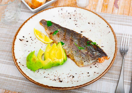 Plate with fried trout fillet with avocado in restaurante closeupの写真素材
