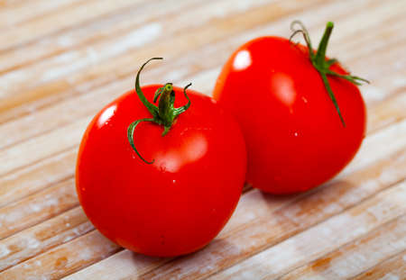 Image of red tomatoes on wooden table in kitchenの写真素材