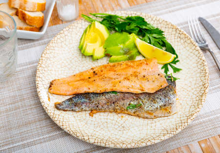 Fried trout fillet served with avocado is healthy dish in kitchenの写真素材