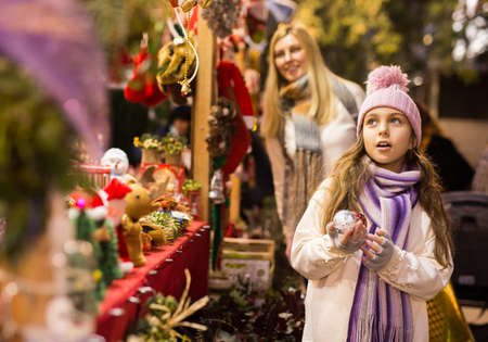 Enthusiastic teenager girl picking tree decorations at street marketの写真素材