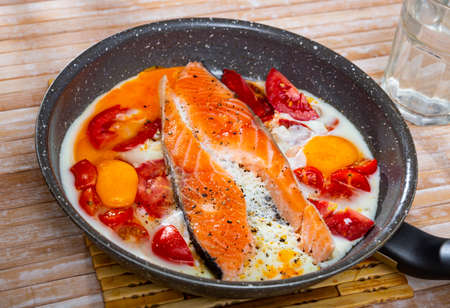 Scrambled eggs and with salmon and tomatoes on fry panの写真素材