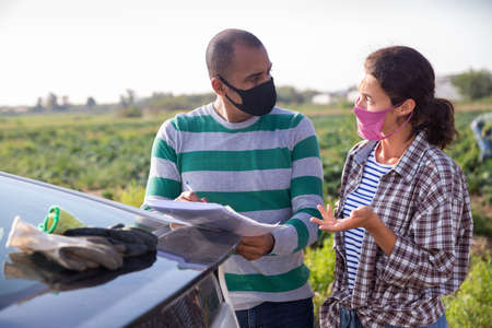 Farmers in masks discussing documents near carの写真素材