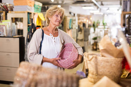 Portrait of senior woman choosing various household goods in storeの写真素材