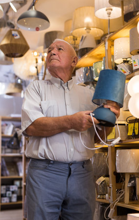 Mature man choosing table lamp at shop