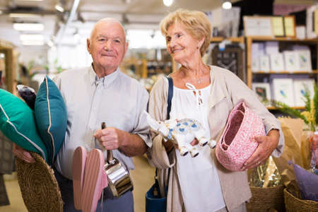 Senior married couple holding purchases and walking in household goods storeの写真素材