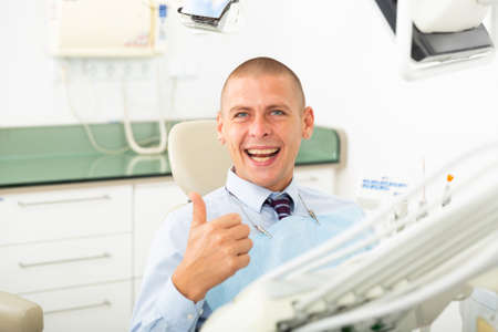 Portrait of a positive man patient sitting in a dental chairの写真素材