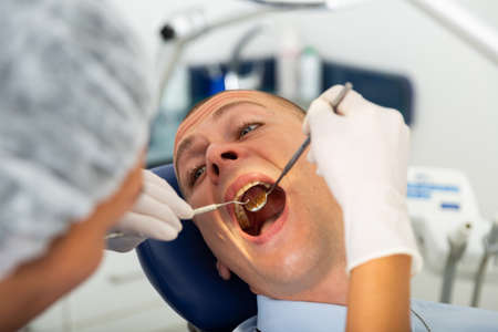 Female dentist examines the oral cavity of female patient. Dental treatment in dental clinicの写真素材