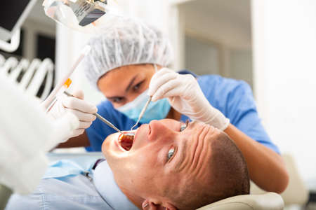 Dentist inspects male patient teethの写真素材