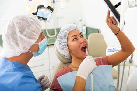 Qualified man dentist conducts an examination of a woman patient using an apexlocatorの写真素材