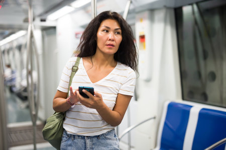 Woman with smartphone standing in metropolitan trainの写真素材