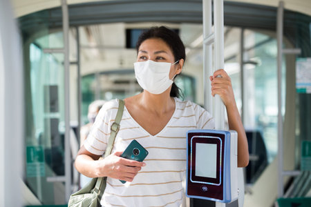 Woman in mask standing in tramの写真素材