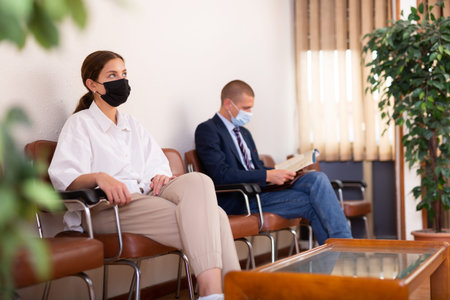 Focused girl in a protective mask sits in the lobby