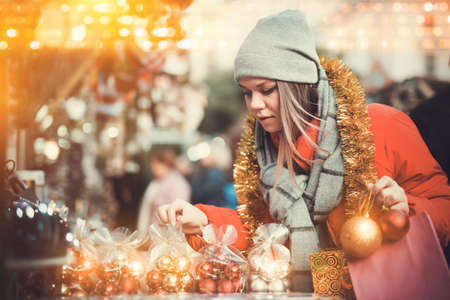 Young female near counter with xmas gifts on street marketの写真素材