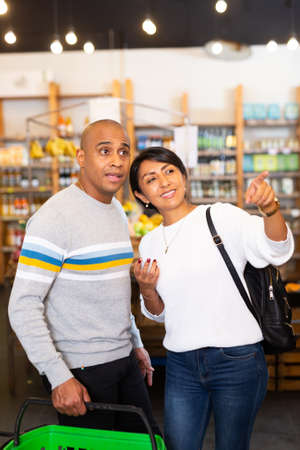 Happy hispanic couple choosing foods in grocery shopの写真素材