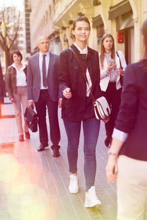 People in formal wear walking down street in cityの写真素材