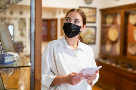 Portrait of female visitor in protective face mask with paper guide at paintings expositionの写真素材