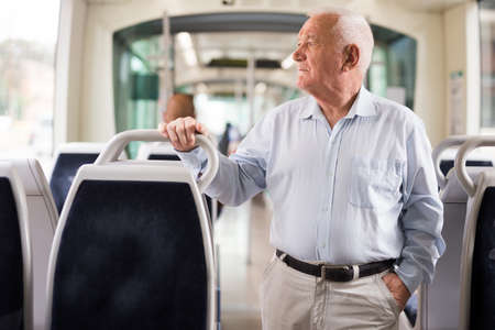 Elderly man standing in tramの写真素材